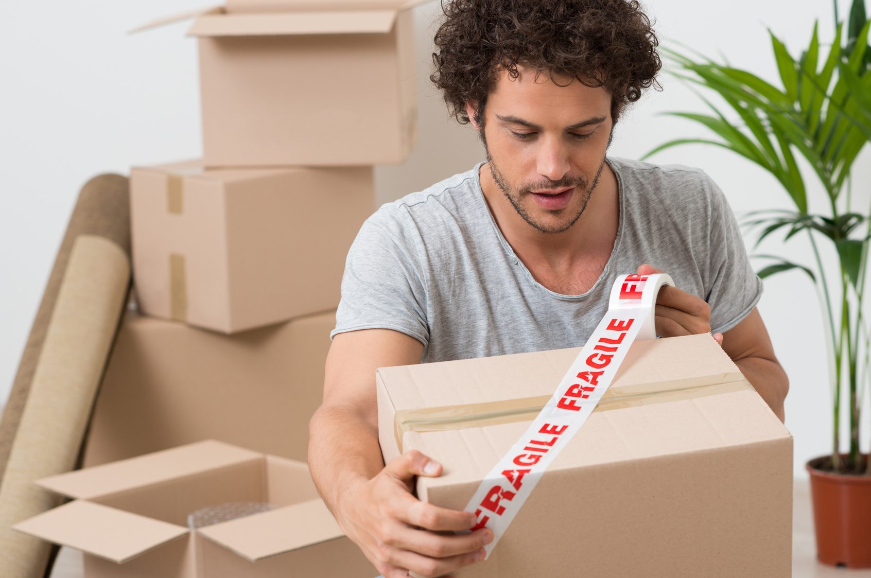 Portrait Of A Young Man Packing Cardboard Box With Fragile Sellotape